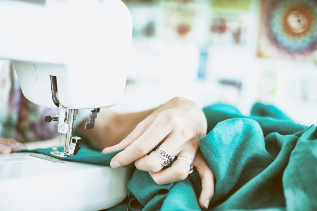 10 Essential Clothing Alterations Explained | Online Alterations & Tailor Guide 2 A woman's hand feeding fabric through a sewing machine as she alters a garment